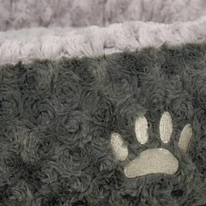 Nahaufnahme des weichen, flauschigen grauen Stoffes des Nobby Donut SEOLI - Hundebettes mit Wirbelmuster und cremefarbenem, gesticktem Pfotenabdruck. Oben ist ein leicht lavendelfarbener, strukturierter Rand zu sehen.